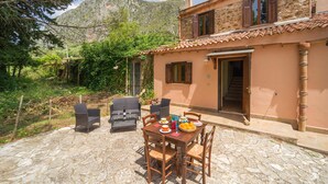 A stone patio with a table set for dining, surrounded by wicker chairs. - Cozy home in San Giuseppe Jato with swimming pool (San Giuseppe Jato)
