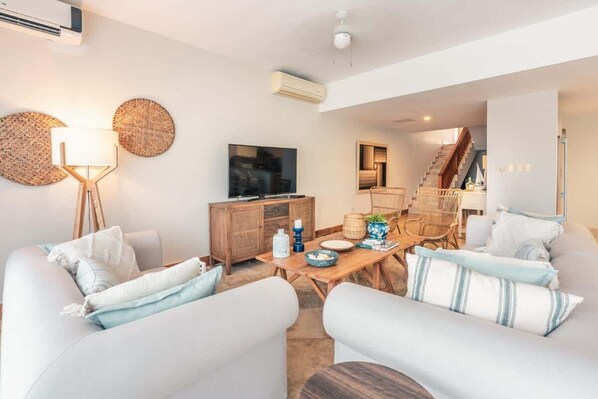 A modern living room with a sofa set, a wooden dining table, and a television. - Ocean View Villa with Pool & BBQ in Samana (Samaná)