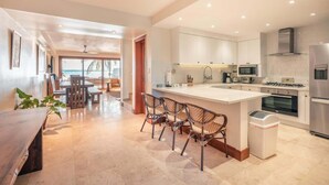 A modern kitchen with white cabinets, a central island with bar stools, and a view to the outside. - Ocean View Villa with Pool & BBQ in Samana (Samaná)