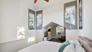 A bedroom with a large bed, a wooden headboard, and a skylight. There is a desk with a lamp and a chair in the corner. - Cooper Cay - Marsh views, Pet friendly, Screen porch, Walk to beach & restaurants (Folly Beach)
