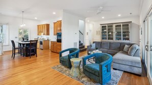 A spacious living area with a gray sofa, blue armchairs, and a dining table with chairs. - Cooper Cay - Marsh views, Pet friendly, Screen porch, Walk to beach & restaurants (Folly Beach)