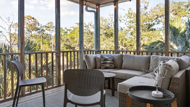 A covered outdoor seating area with a sofa, chairs, and a small table. - Cooper Cay - Marsh views, Pet friendly, Screen porch, Walk to beach & restaurants (Folly Beach)