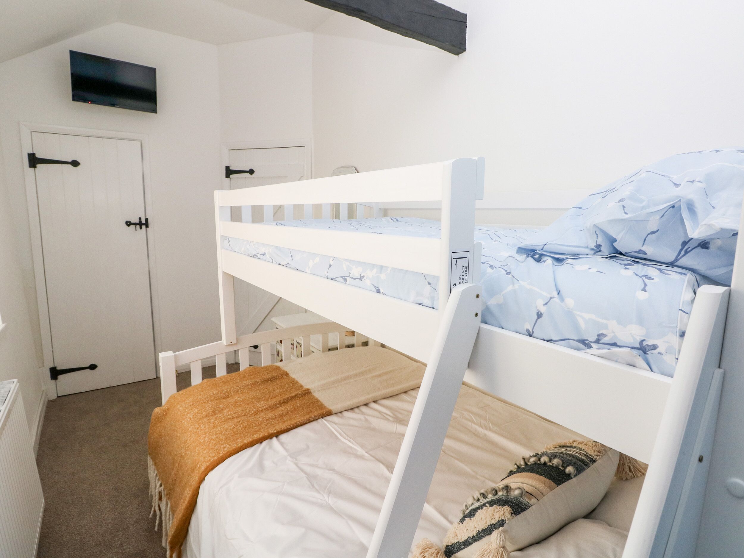 A bunk bed with a white frame and a blue floral bedspread.