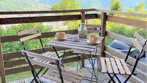 A wooden deck with a table and chairs, overlooking a mountainous landscape. - Lovely apartment in Gérardmer with house sea view (Gérardmer)