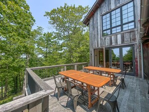 A wooden deck with outdoor seating, a railing, and a building with large windows. - Stunning Luxury Home! Direct Ski Access and Hot Tub (McHenry)