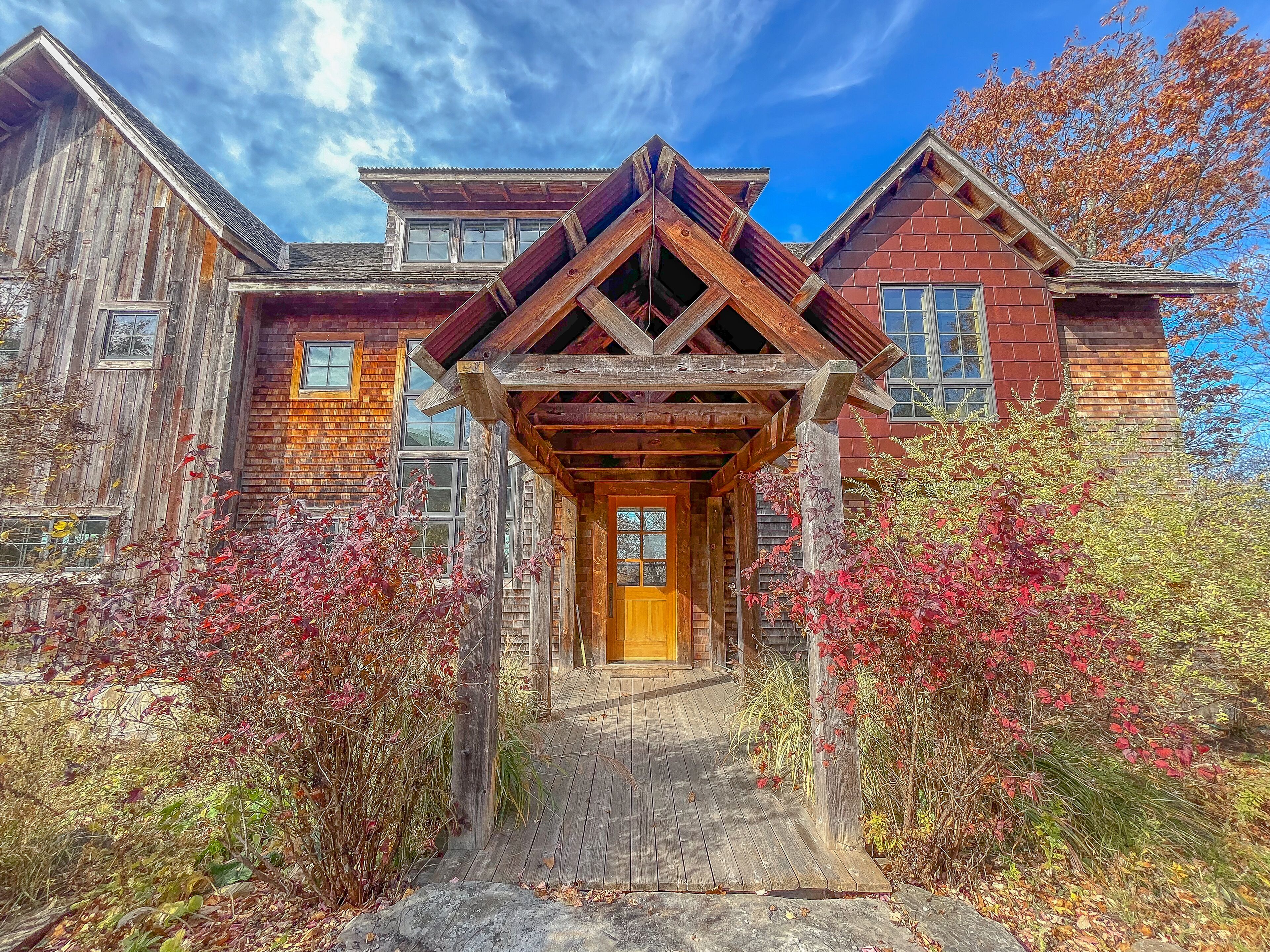 A rustic wooden house with a wooden porch and a brick section.