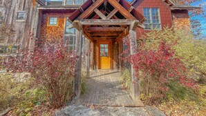 A rustic wooden house with a wooden porch and a brick section.