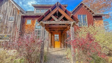 A rustic wooden house with a wooden porch and a brick section.