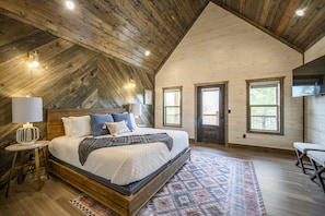 Une chambre spacieuse avec un grand lit, un plafond en bois et de nombreuses fenêtres.
