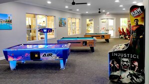 A pool table area with a pool table, a pool cue, and a poster of Superman. - Free Water Park! August on Sale Now! (Kissimmee)