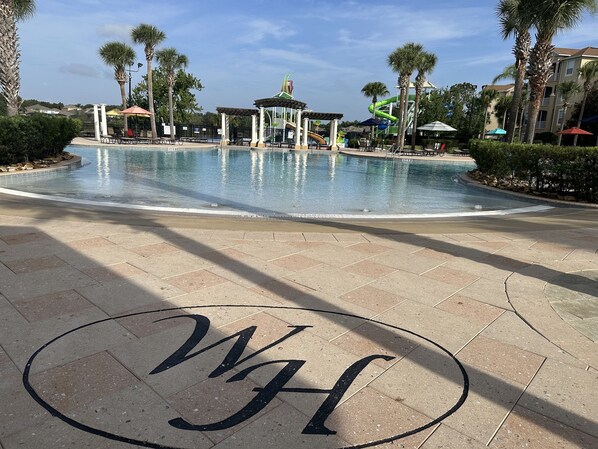 A swimming pool with a pavilion, palm trees, and a clear sky.
