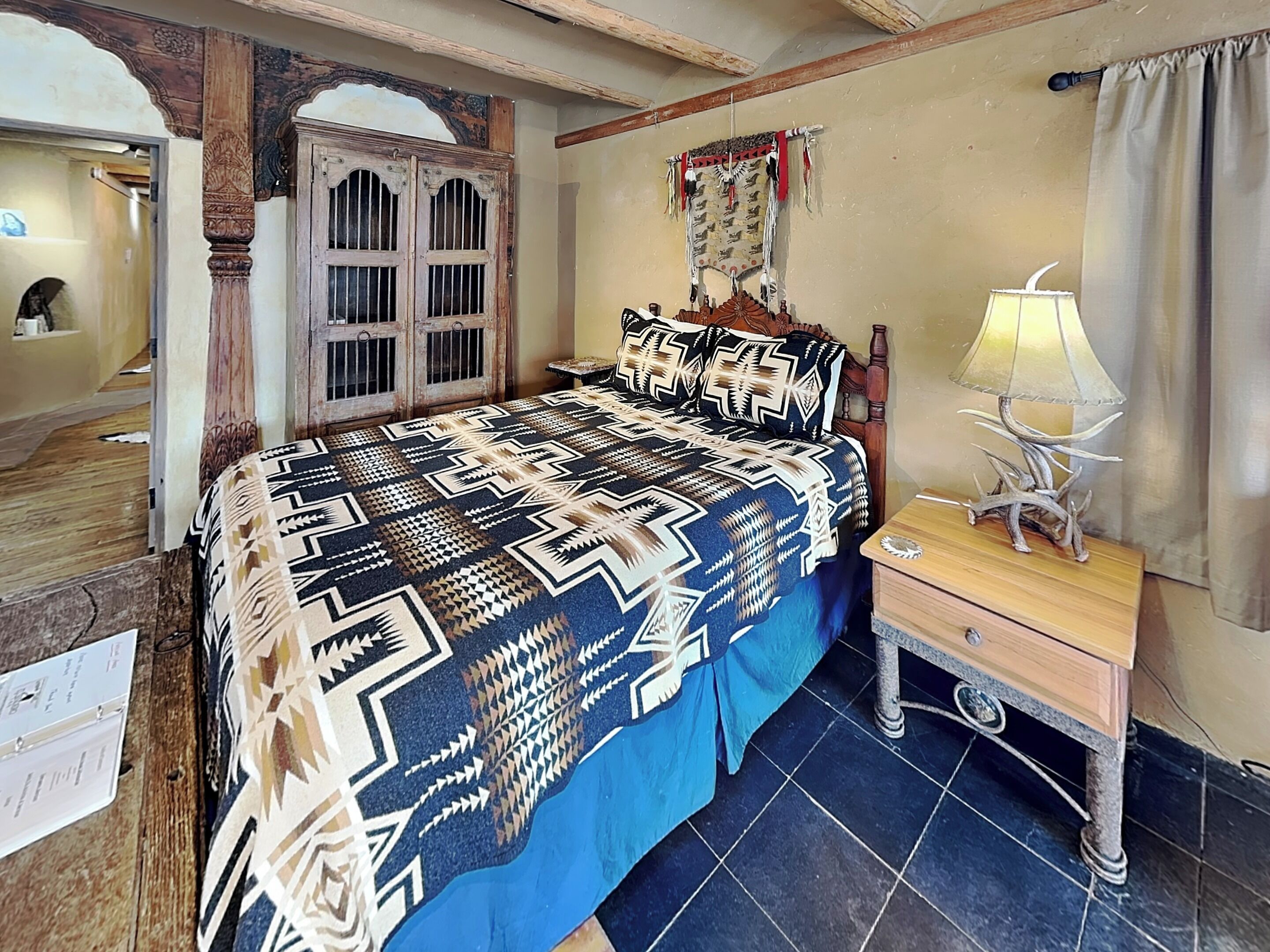 A bedroom with a bed, a nightstand, a lamp, and a decorative headboard.