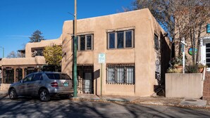 Un edificio de fachada color beige, un coche aparcado y un cartel que indica zona de carga.