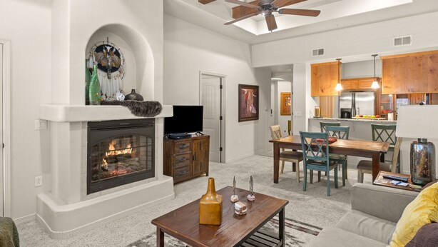 Un salon spacieux avec une cheminée, un coin repas et une cuisine dotée de meubles en bois.