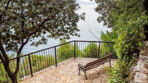 A stone-paved terrace with a metal railing and a wooden bench overlooking a body of water. - Beautiful apartment in Moscenicka Draga with WiFi (Moscenicka Draga)