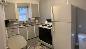 A compact kitchen with a refrigerator, stove, sink, and a small dining area. - Cheerful 3 bedroom cottage with River access. (Clay Township)