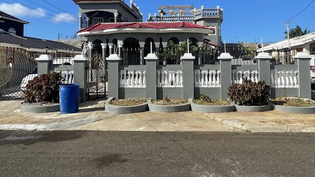 A large, gated residential property with a central pavilion, multiple balconies, and a red roof. - Spacious 9 BED family sized house in a gated community (Trelawny Parish)