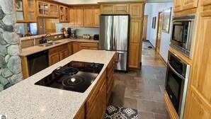 A kitchen with granite countertops, wooden cabinets, a stainless steel refrigerator, and a built-in stove.