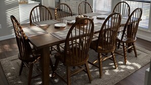 A dining area with a wooden table and chairs, a chandelier, and a kitchen in the background. - A Dream Come True Lake House  - The prettiest sunset view on the lake! (Marquez)