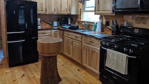 A kitchen with wooden cabinets, a black refrigerator, a stove, and a microwave.