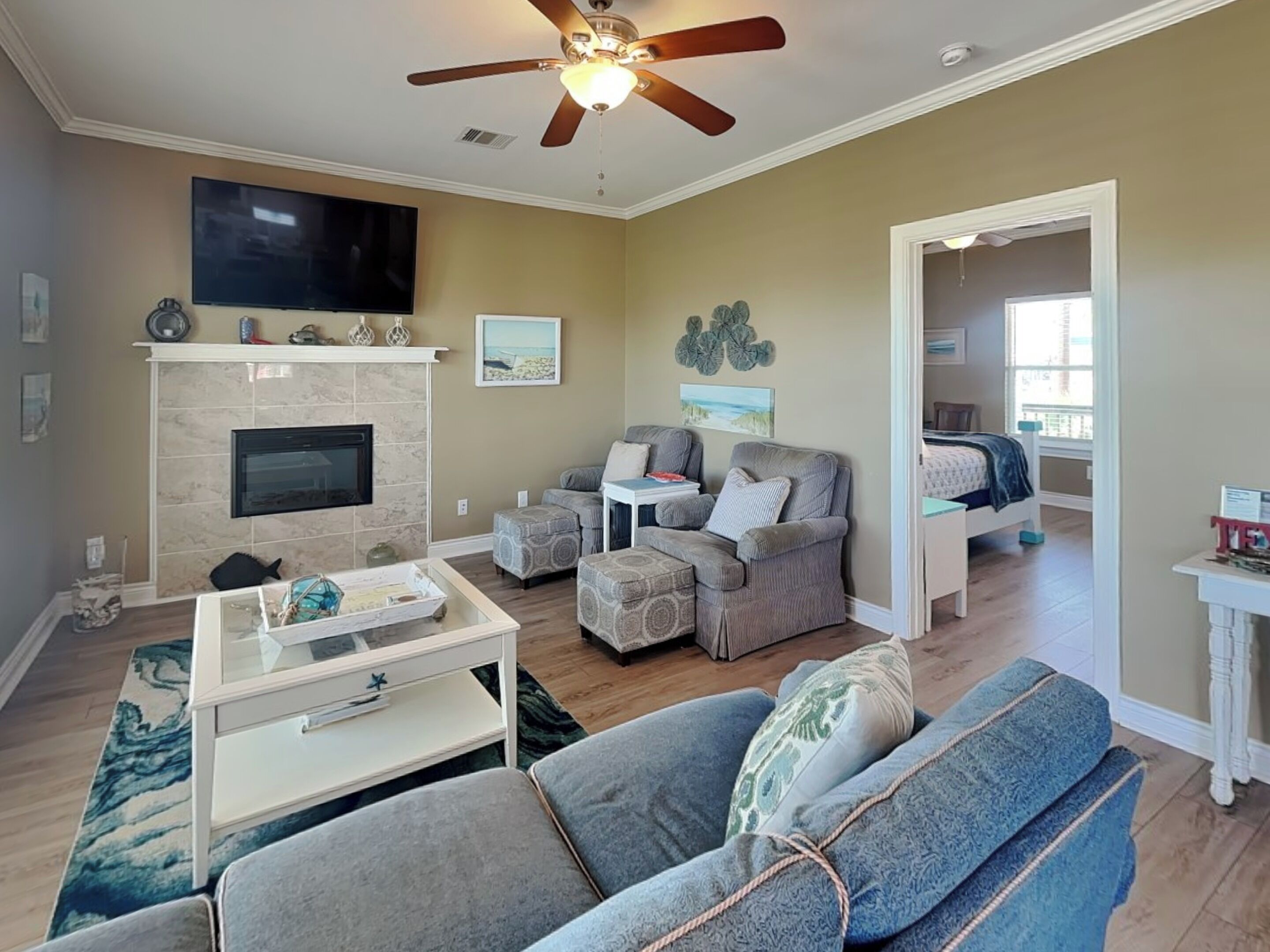 A living room with a fireplace, a ceiling fan, a television, and a sofa.