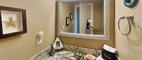 A bathroom with a marble sink, a framed seastar decoration, a mirror with a textured frame, and a towel rack with a towel.