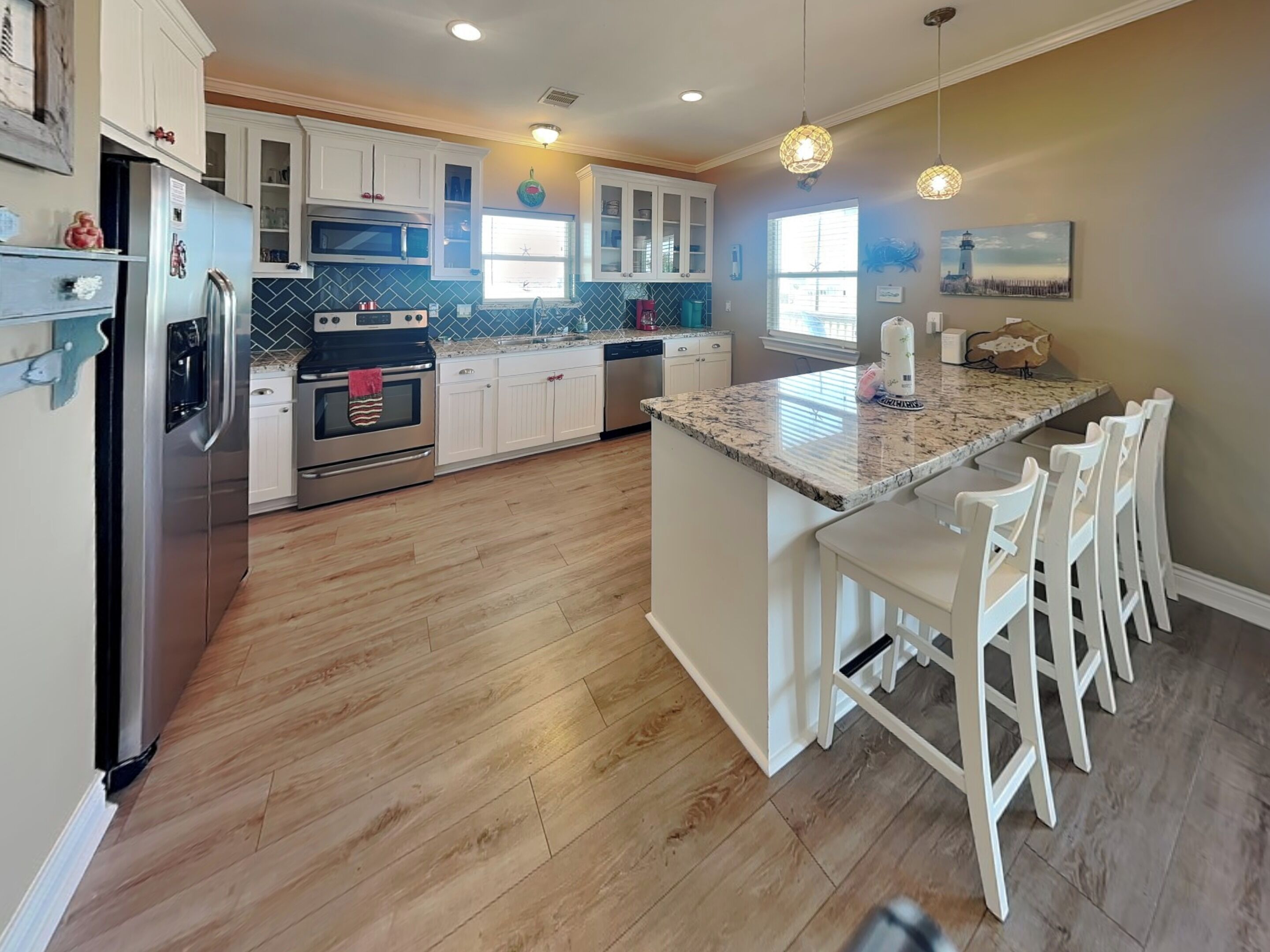 A kitchen with white cabinets, a granite countertop, and a central island with bar stools.