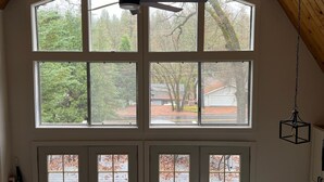 Una habitación con ventanas amplias, un ventilador de techo y una lámpara colgante.