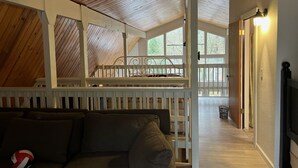 Una habitación acogedora con techo de madera, literas, baranda blanca y vistas amplias por ventanas grandes.
