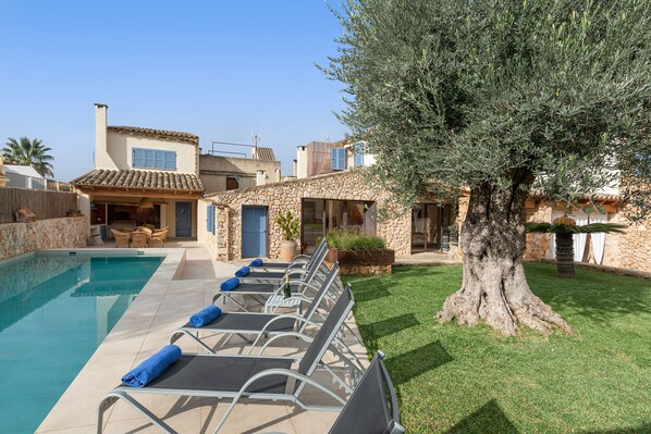A poolside area with lounge chairs, a stone building, and a large tree. - CAN FONT (COSTITX) - Stunning villa with private pool and free WiFi. (Costitx)