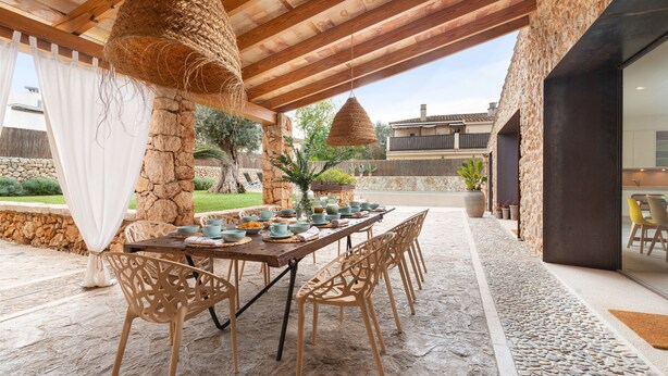 An outdoor dining area with a stone pillar, wooden ceiling, and a table set with chairs and dishes. - CAN FONT (COSTITX) - Stunning villa with private pool and free WiFi. (Costitx)