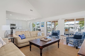 A spacious living room with a beige sofa, a coffee table, and patterned armchairs. - Flamingo House by Miss Kitty’s (Rockport)