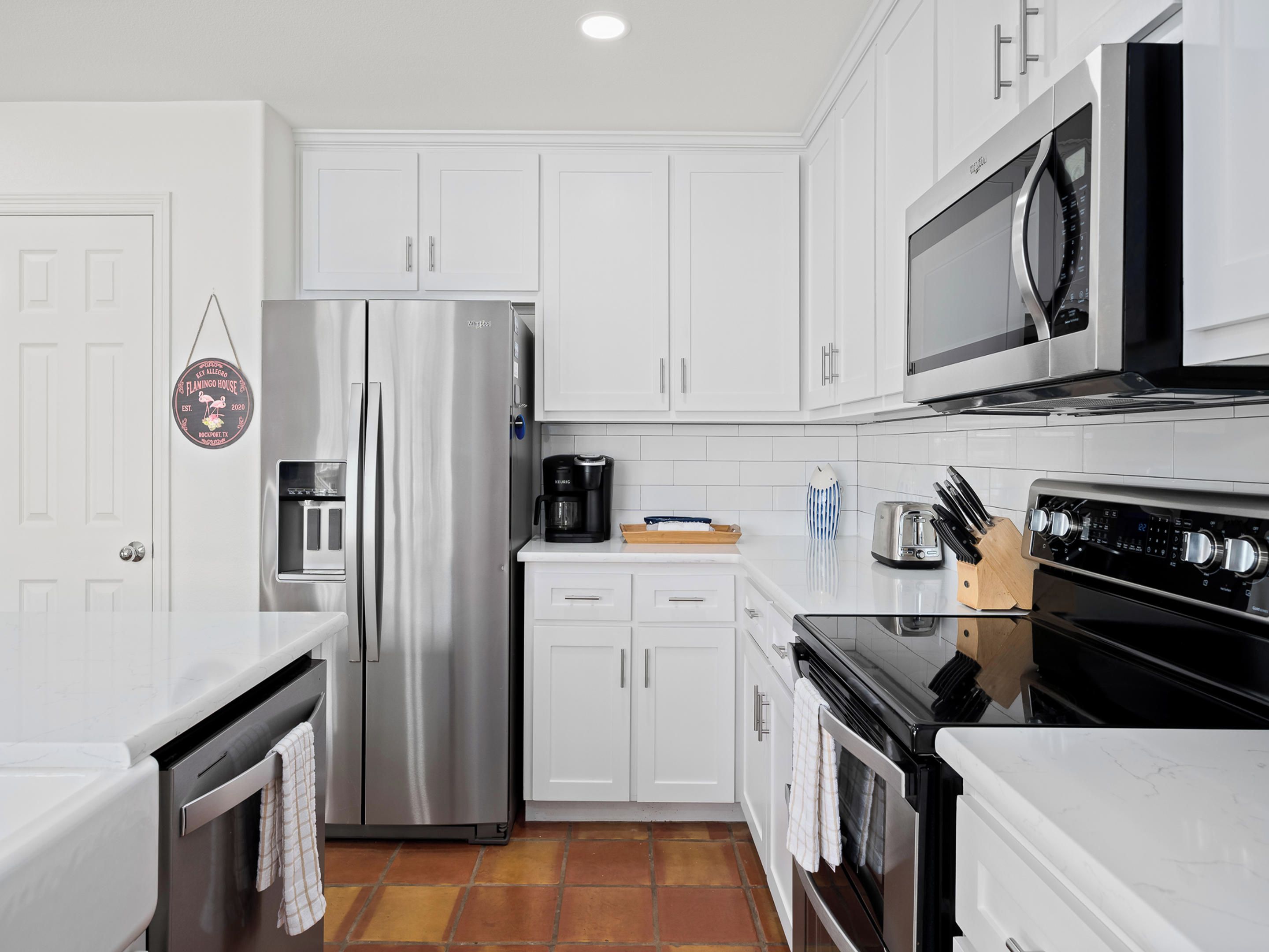 A modern kitchen with white cabinets, stainless steel appliances, and a tiled backsplash.