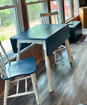 A room with a wooden table and chairs, large windows, and a view of the outdoors.