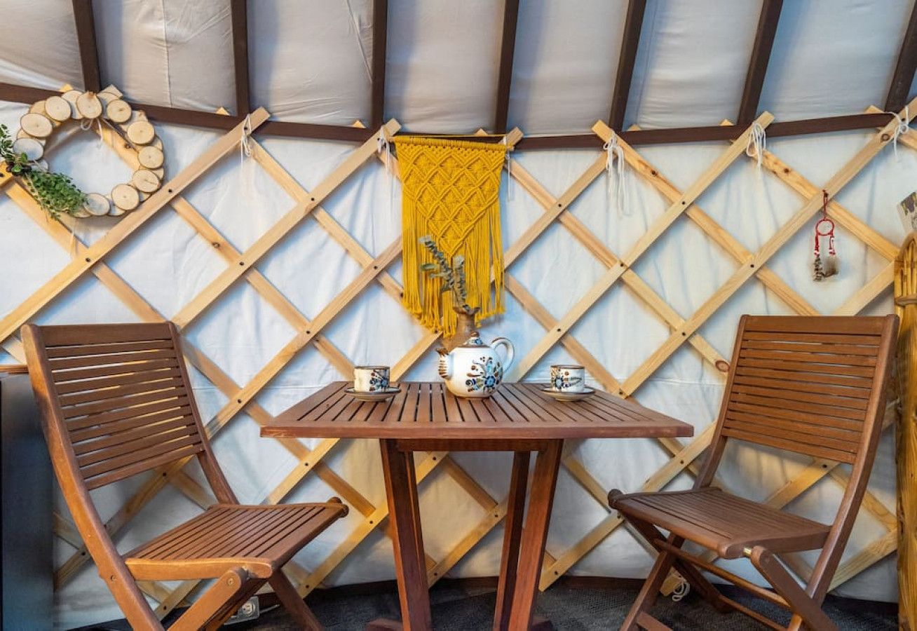 Een houten tafel met twee stoelen, een decoratieve wandversiering en een kleine plant.