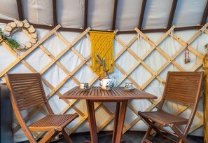 A wooden table with two chairs, a decorative wall hanging, and a small plant.
