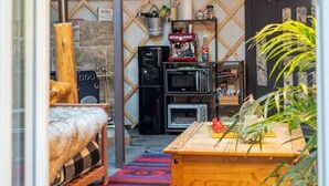 A cozy interior with a curved ceiling, a wooden table, a sofa, and a coffee machine.