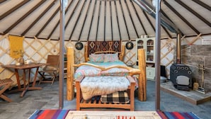 A yurt with a wooden bed, a small table, and a chair.