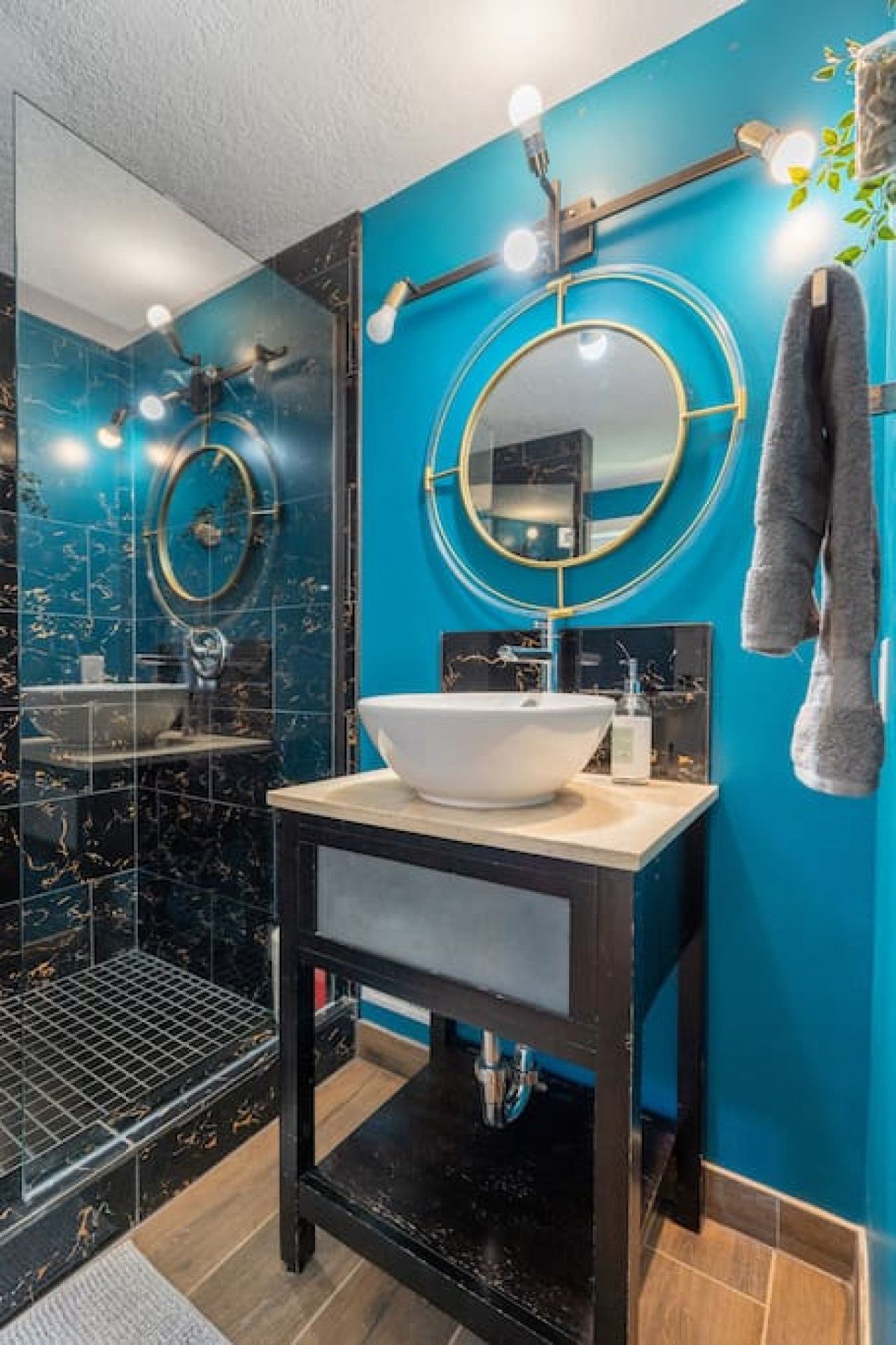 A modern bathroom with a large mirror, a white sink, and a shower.