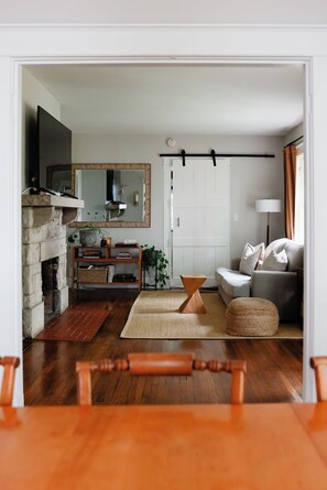 A living room with a fireplace, a sofa, a coffee table, and a TV. - The Bellmore Cottage (Nashville)