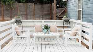 A wooden deck with white railings and a white bench with cushions. - The Bellmore Cottage (Nashville)