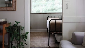 A compact room with a bunk bed, a small table with a plant, a TV, and a sliding door leading to a balcony. - The Bellmore Cottage (Nashville)