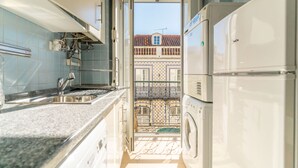 A kitchen with a sink, stove, and a washing machine. - Bright 2BR Baixa Flat w/ Elevator | Balcony, Downtown Views & Full A/C (Lisboa ciudad)