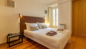 A bedroom with a large bed, bedside tables, a radiator, and a wardrobe. - Bright 2BR Baixa Flat w/ Elevator | Balcony, Downtown Views & Full A/C (Lisboa ciudad)