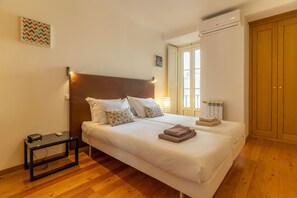 A bedroom with a large bed, bedside tables, a radiator, and a wardrobe.