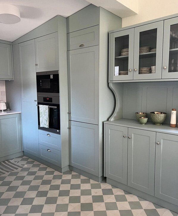 A kitchen with grey cabinets, a microwave, and a built-in oven. There are two small decorative bowls on the counter.