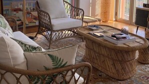 A spacious living room with wicker furniture, large windows offering a view of the countryside, and a painting on the wall. - Detached house in the Douro with stunning river and mountain views (Mesão Frio)