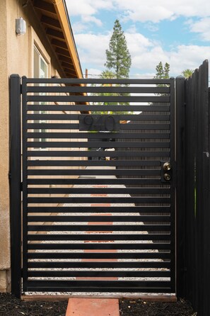 A black metal gate with horizontal slats and a numeric keypad lock.