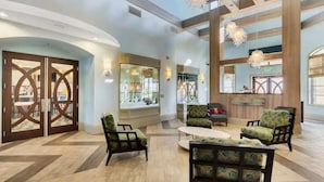 A spacious lobby with a modern design, featuring a reception desk, comfortable seating areas, and large windows allowing natural light.