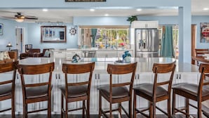Uma cozinha moderna com armários brancos, eletrodomésticos de aço inoxidável e uma ilha grande com banquetas.